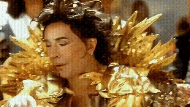 a close up of a woman wearing gold feathers and a crown