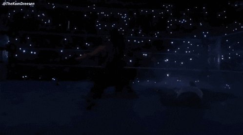 a wrestler is kneeling down in the middle of a ring while another wrestler lays on the floor