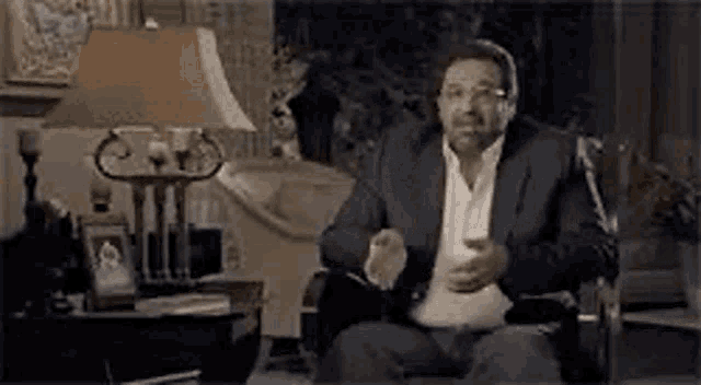 a man in a suit is sitting in a chair wearing headphones and a lamp .