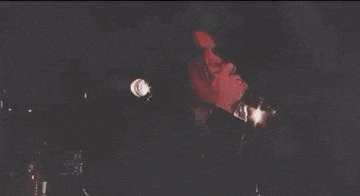 a man is playing a guitar and singing into a microphone while sitting on the floor .