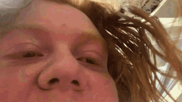 a close up of a person 's face with long red hair