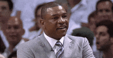 a man in a suit and tie is smiling in front of a crowd of people
