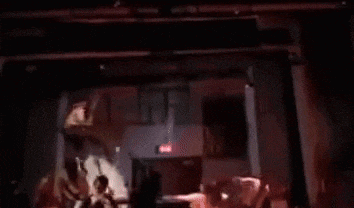 a group of people standing in a dark room with a red exit sign .