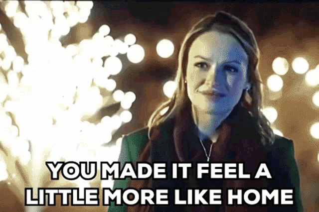 a woman is standing in front of a christmas tree with the words `` you made it feel a little more like home ''
