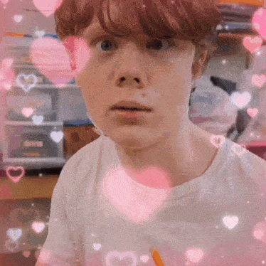 a young boy is surrounded by pink hearts and looking at the camera