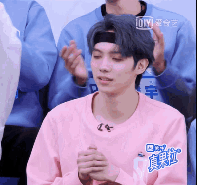 a young man wearing a pink sweater with ioiyi on the bottom