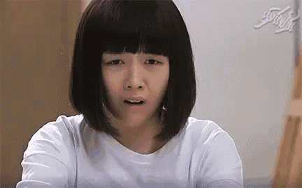 a woman with short black hair is making a funny face while wearing a white shirt .