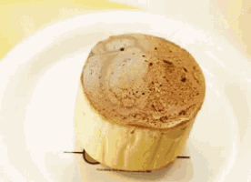 a white plate topped with a cupcake with a chocolate frosting