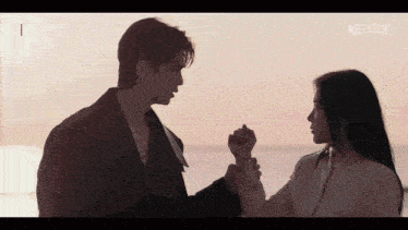 a man and a woman are holding hands in front of the ocean and netflix is visible in the corner