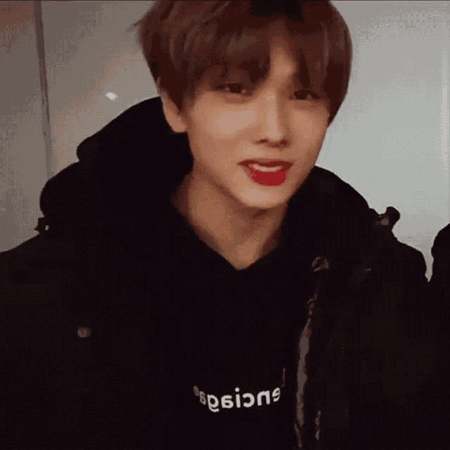 a close up of a young man wearing a black hoodie and a black jacket .