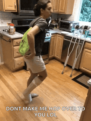 a woman with crutches is dancing in a kitchen with the words " dont make me hop over to you lol " on the bottom