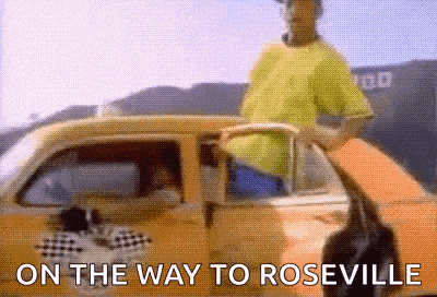 a man in a yellow shirt is standing next to a yellow car with the words `` on the way to roseville '' .