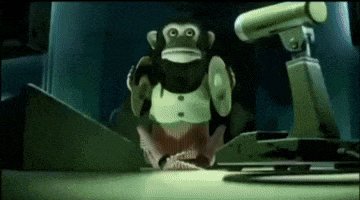 a toy monkey is sitting on a desk in front of a camera