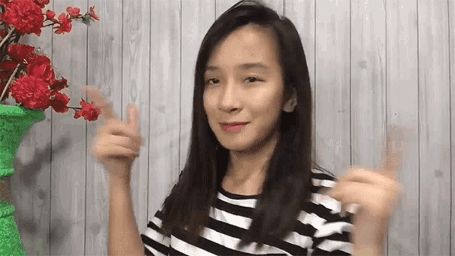 a woman in a striped shirt is giving a thumbs up .