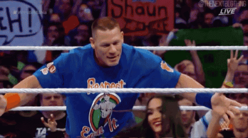 a man in a wrestling ring wearing a blue shirt that says respect