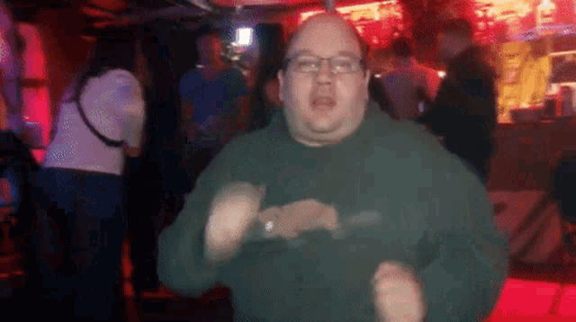 a man in a green shirt is dancing in a club