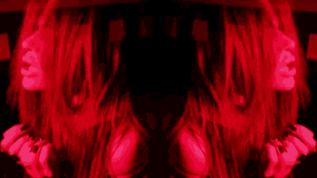a woman with long red hair is reflected in a red light