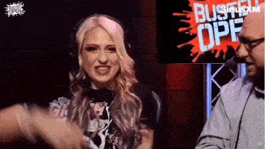 a woman wearing headphones is talking to a man in front of a sign that says buster opf
