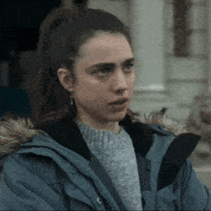 a woman wearing a grey sweater and a blue jacket