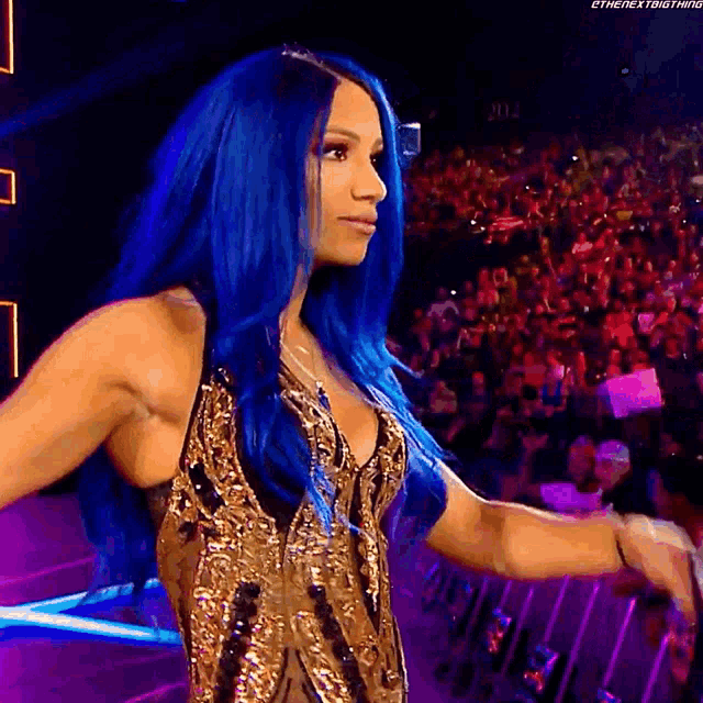 a woman with blue hair is standing in front of a crowd wearing a gold dress .