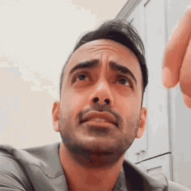 a man with a beard is making a funny face with his hand .