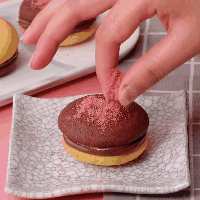 a person is sprinkling pink sugar on a cookie