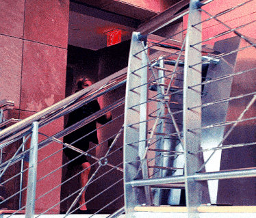 a woman is walking down a staircase with a red exit sign above her
