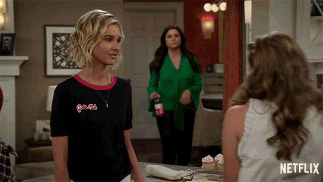 a woman wearing a black shirt that says girls club stands in front of two other women