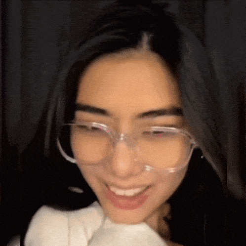 a close up of a woman wearing glasses and a white shirt .