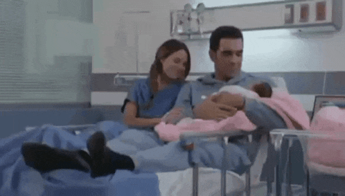 a man and a woman are holding a newborn baby in a hospital bed .