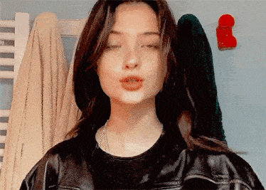 a woman wearing a black leather jacket is making a funny face .