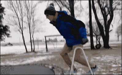 a man in a blue jacket is using a walker in the snow .