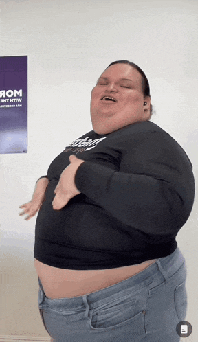 a woman with a very large belly is dancing in front of a poster that says rom