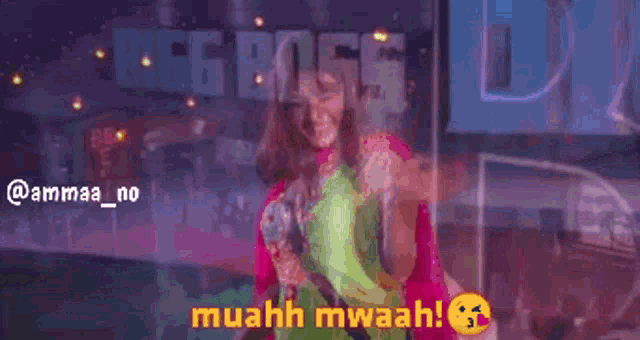 a woman in a pink and green dress is dancing with the words muahh mwaah behind her
