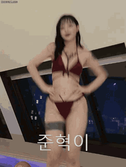 a woman in a red bikini is dancing in front of a window with chinese writing on it