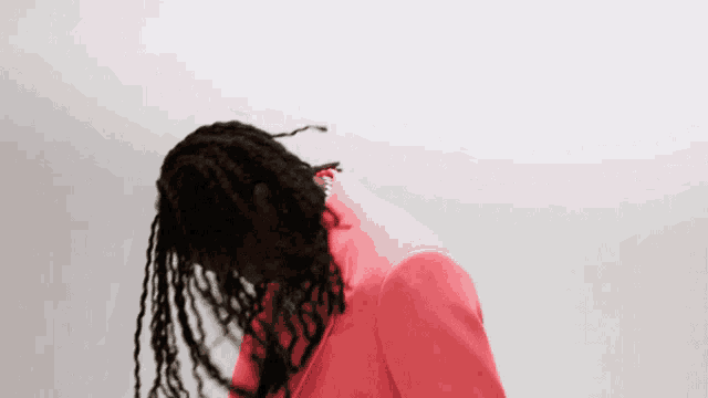 a man with dreadlocks is wearing a pink suit jacket
