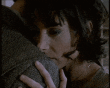 a close up of a woman hugging a man 's shoulder