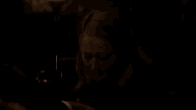 a woman is sitting in a dark room looking at her phone