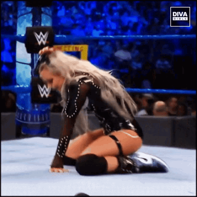 a woman is kneeling down in a wrestling ring with the diva girls logo on the bottom