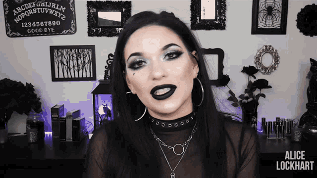 a woman with black lipstick is in front of a ouija board