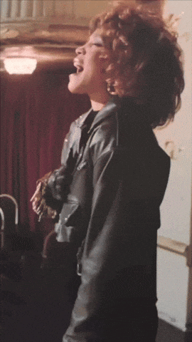 a woman in a black leather jacket is singing