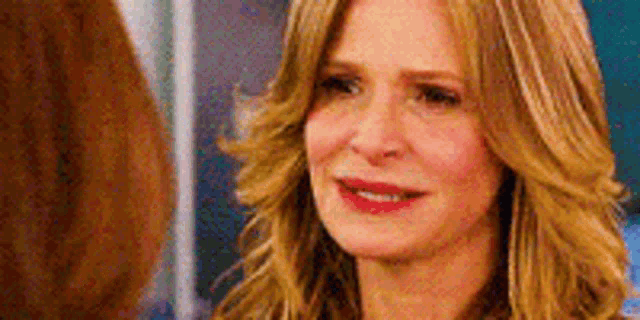 a close up of a woman 's face with long blonde hair and red lips .