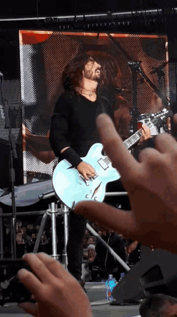 a man playing a guitar on stage with a crowd watching