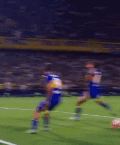 a blurry picture of a soccer game with a few players in blue and yellow