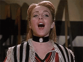 a woman wearing a choker and a striped shirt is singing .