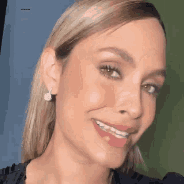 a close up of a woman 's face with braces on her teeth and earrings .