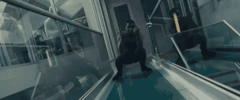 a man is squatting on a glass floor in front of a window in a room .