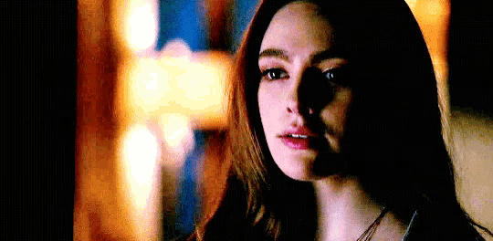 a close up of a woman 's face with a dark background and a shadow on her face .