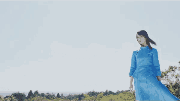 a woman in a blue dress is standing in a field