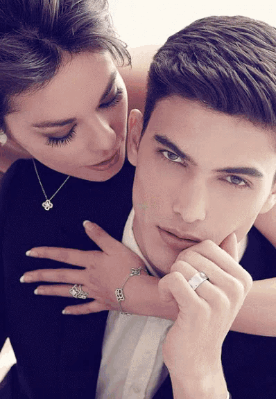 a man and a woman are posing for a picture and the woman is wearing a necklace and bracelet